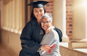Graduation, university and portrait of mother with girl at academic ceremony, celebration and achievement. Family, education and mom hugging graduate daughter with degree or diploma on college campus